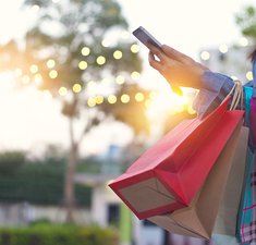Woman using smartphone with shopping bag in hands
